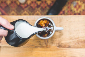 The image shows raw almond milk being poured into a cup.